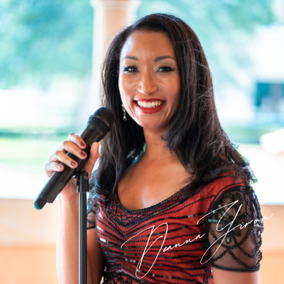 Deanna holding a microphone wearing a red 20s flapper dress.